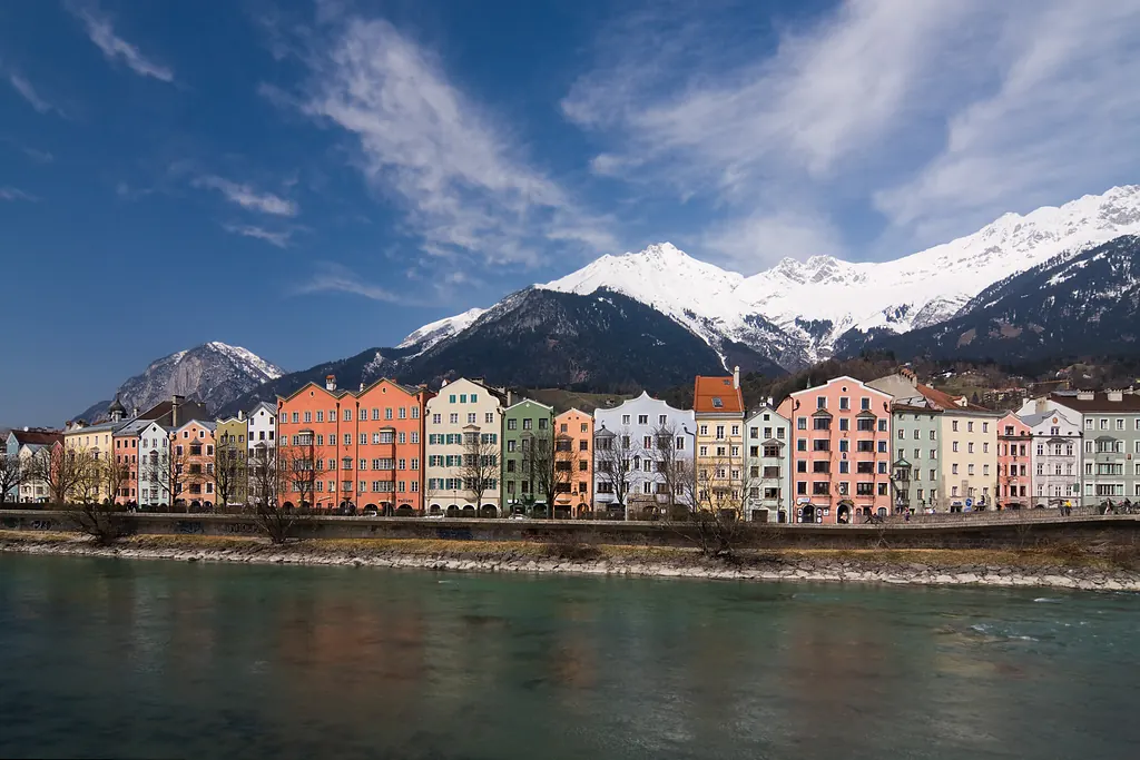 Innsbruck'ta Inn Nehri kıyısındaki renkli evler ve arkalarında karla kaplı dağ silsilesi