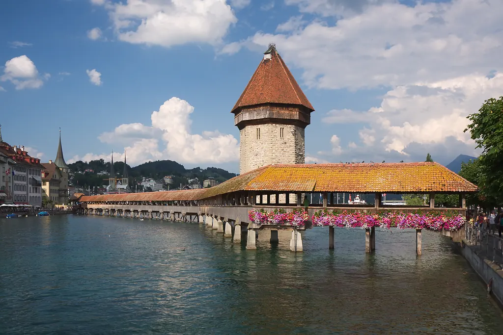 Luzern'de Reuss Nehri üzerindeki çiçeklerle bezeli ahşap Kapellbrücke ve taş Su Kulesi, arkada şehir