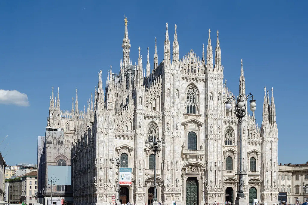 Milano Katedrali'nin sivri kuleli beyaz mermer cephesi, Piazza del Duomo'dan açık gökyüzü altında
