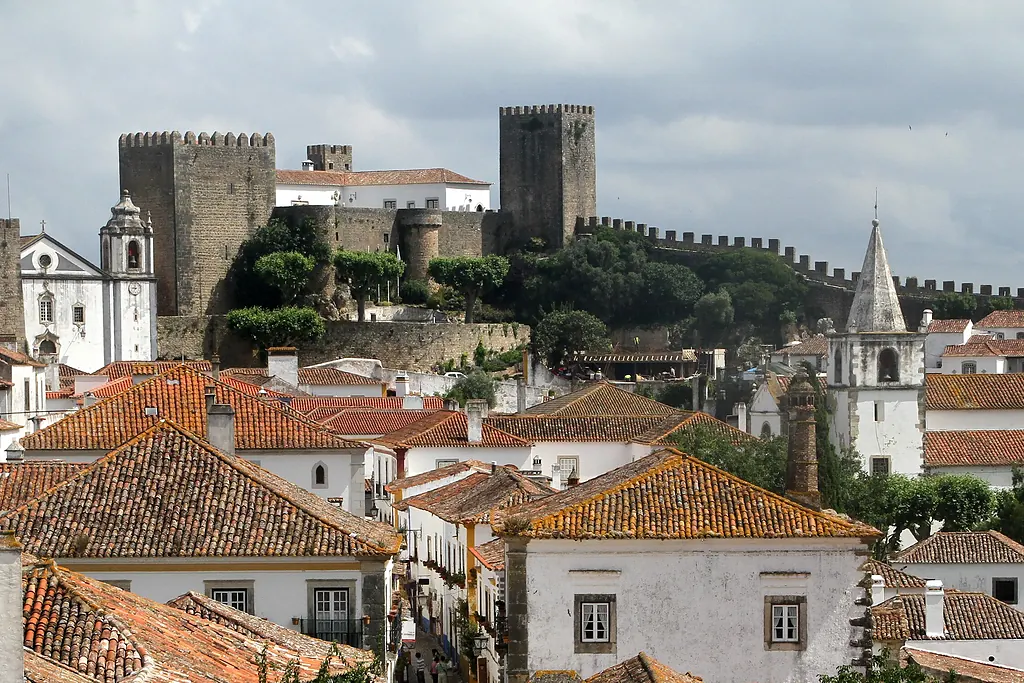 Óbidos'un kırmızı kiremitli çatıları, beyaz kilise kuleleri ve arkada kale ile sur kuleleri