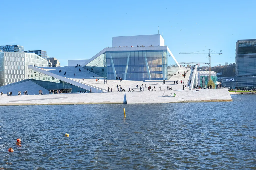 Oslo Opera Binası'nın beyaz mermer çatısı ve önündeki Oslofjord'un mavi suyu, açık havada
