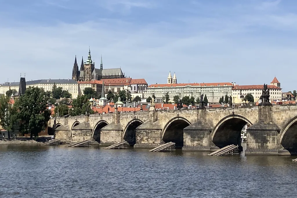 Vltava Nehri üzerindeki Karlov Köprüsü'nün taş kemerleri ve arkada yükselen Prag Kalesi