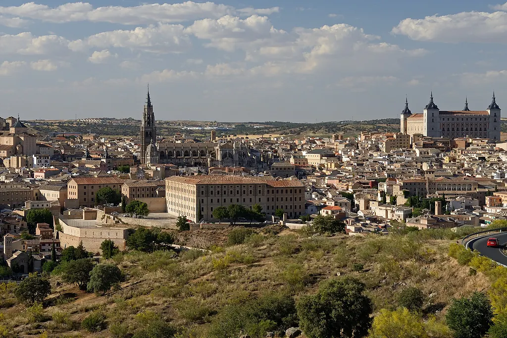Toledo'nun tarihî şehir silueti; solda katedral kulesi, sağda Alcázar, önde yamaç ve yol